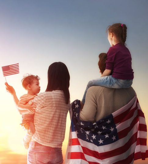 Patriotic holiday. Happy family, parents and daughters children girls with American flag outdoors. USA celebrate 4th of July.